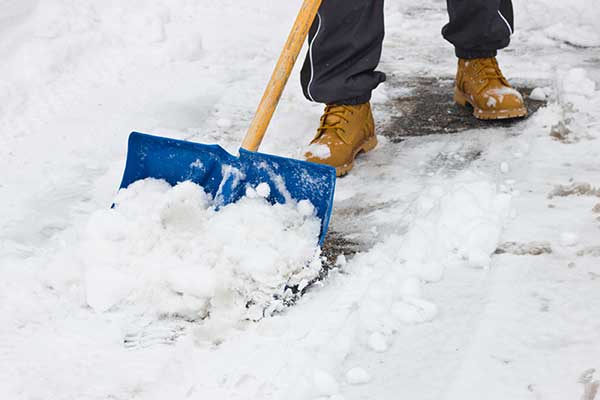 Close up of someone clearing a path through the snow with a blue shovel